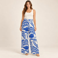 Modelo virtual creada con IA — ivory white wide-leg trousers with exact large cobalt blue tropical leaves and floral print, blue waist button